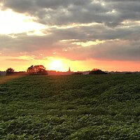Sonnenuntergang über Feld und Kirchturm